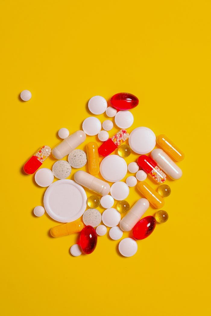 Services A collection of diverse tablets and capsules on a vibrant yellow background, symbolizing healthcare and medication.